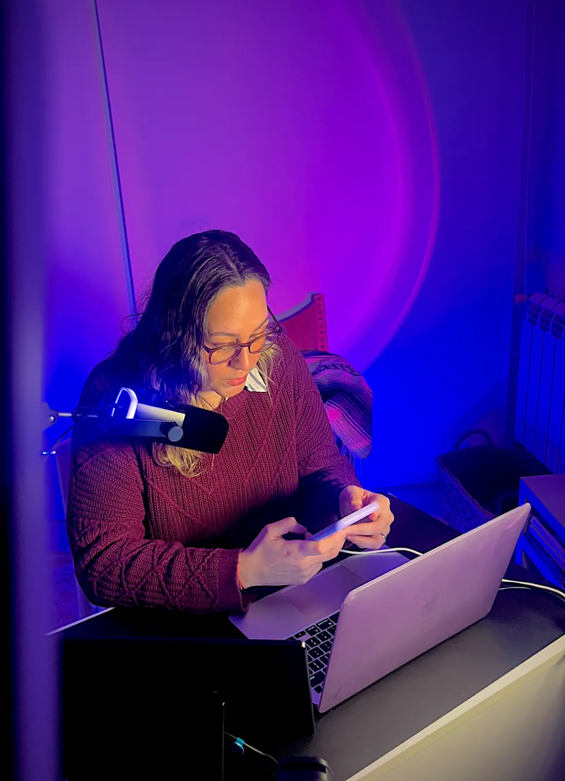 Andy in her home studio, filming a reel on her phone at the desk